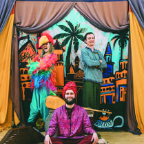 Osoby w orientalnych strojach na scenie teatralnej.