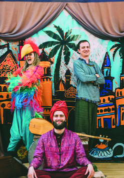 Osoby w orientalnych strojach na scenie teatralnej.