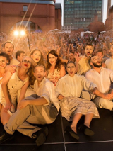 Grupa teatralna ubrana w kostiumy sceniczne pozuje do zdjęcia razem z widownią.