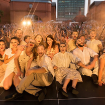 Grupa teatralna ubrana w kostiumy sceniczne pozuje do zdjęcia razem z widownią.