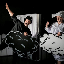 Zdjęcie, na czarnym tle, stoją aktorzy w czarno - białych strojach i trzymają w rękach czarne i białe chmurki.