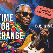 Czarnoskóry artysta w ciemnych okularach i kolorowym garniturze gra na gitarze. Białe napisy z tytułem wydarzenia.