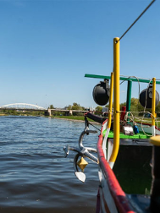 Dziób statku na Warcie. Widoczna kotwica. W dali widać most.