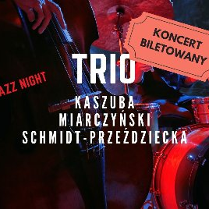 Zdjęcie przedstawia plakat koncertu jazzowego. Przedstawia trio muzyków występujących na scenie. Muzycy grają na kontrabasie, perkusji i fortepianie. Plakat jest czerwono-czarny i zawiera duży bilet z napisem "KONCERT BILETOWAN". Plakat zawiera również nazwiska muzyków: Kaszuba, Miarczyński i Schmidt-Przeździecka. Całość oddaje dynamiczną i żywą atmosferę występu jazzowego na żywo.
