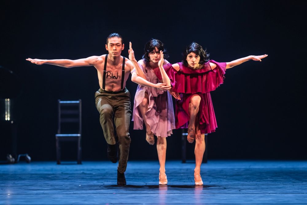 Troje tancerzy na scenie w synchronicznym ruchu.