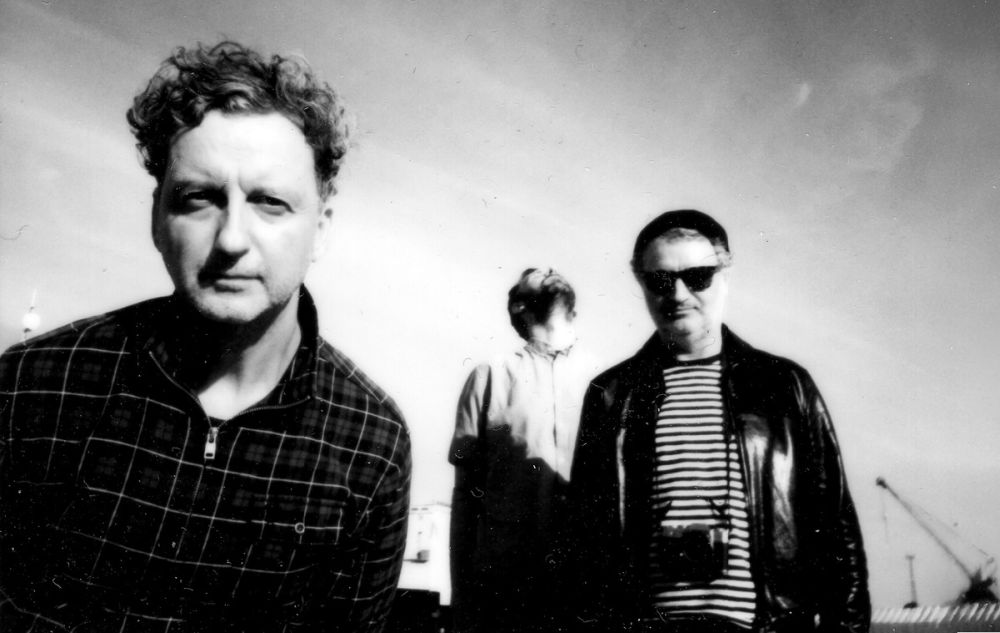 Trzech mężczyzn na rozmazanym, czarno-białym zdjęciu.