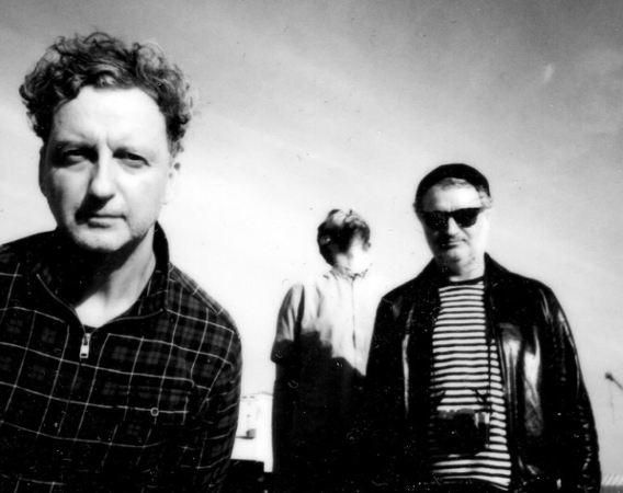 Trzech mężczyzn na rozmazanym, czarno-białym zdjęciu.