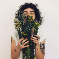 Młoda kobieta trzyma w ręku bukiet roślin i wdycha ich zapach.