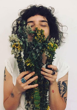 Młoda kobieta trzyma w ręku bukiet roślin i wdycha ich zapach.