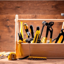 Zdjęcie drewnianej skrzyneczki wypełnionej różnymi narzędziami: młotkiem, śrubokrętami, kluczami...