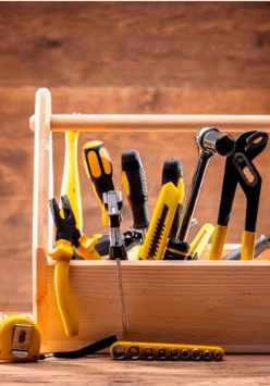 Zdjęcie drewnianej skrzyneczki wypełnionej różnymi narzędziami: młotkiem, śrubokrętami, kluczami...