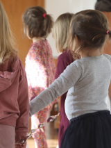 Tańczące dzieci odwrócone tyłem do kamery.