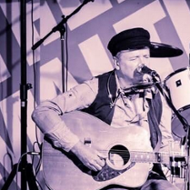 Biało-czarne zdjęcie artysty na scenie.