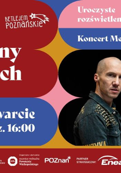 Obraz to plakat jarmarku bożonarodzeniowego w Poznaniu, w Polsce. Na plakacie znajduje się duże, oświetlone drzewo bożonarodzeniowe, mężczyzna w czarnej skórzanej kurtce i tekst "Jarmark Świąteczny Na Targach". Na plakacie widnieją również daty i godziny wydarzeń jarmarku, w tym uroczyste otwarcie, koncert artysty Mezo i zapalenie choinki. Obecne są również loga organizatorów wydarzenia, sponsorów i partnerów.