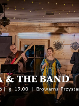 Na scenie zespół składający się z kobiety i czterech mężczyzn. Występują na scenie w drewnianym domu, sufit jest oświetlony lampkami.