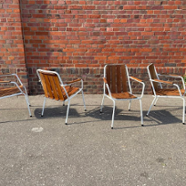 Na zdjęciu ustawione są cztery krzesła. Stoją one przy ceglanej ścianie.