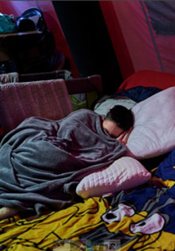 Najprawdopodobniej kobieta śpi pod kocem w jakim miejscu dla uchodźców.