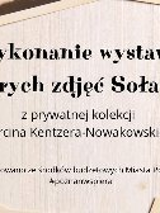 Obrazek reklamuje wystawę starych zdjęć Sołacza. Nazwa wystawy jest wpisana w dekorację w postaci zdjeć, porozrzucanych na brzegach obrazka.