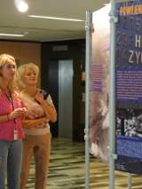 Zdjęcie, grupa osób ogląda wystawę w holu Urzędu Wojewódzkiego w Poznaniu.