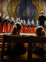 Grupa chórzystek śpiewa na scenie.