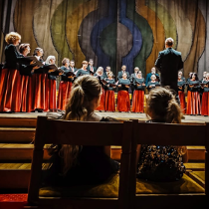 Grupa chórzystek śpiewa na scenie.