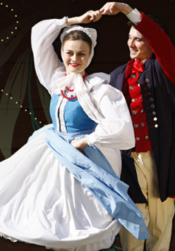 Na zdjęciu znajdują się kobieta i mężczyzna, tańczący wspólnie w strojach ludowych.