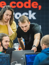 Dwóch mężczyzn i kobieta stoją przy stanowisku komputerowym. Rozmawiają na temat tego, co widzą na ekranie.