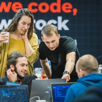 Dwóch mężczyzn i kobieta stoją przy stanowisku komputerowym. Rozmawiają na temat tego, co widzą na ekranie.