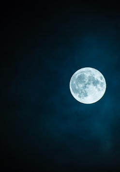 Rozświetlony księżyc w pełni na czystym nocnym niebie.