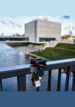 Widok na Wartę i Bramę Poznania: na pierwszym planie poręcz mostu z przypiętymi kłódkami