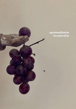 Fragment ekspozycji - dłoń trzymająca kiść winogron