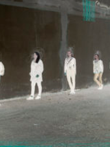 Zdjęcie pięciu kobiet opartych o mur stojących w pewnej odległości od siebie.