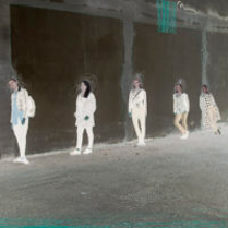 Zdjęcie pięciu kobiet opartych o mur stojących w pewnej odległości od siebie.