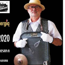 Na zdjęciu starszy mężczyzna w kapeluszu słomkowym - muzyk z przewieszoną przez szyją tarką i trzepaczkami.