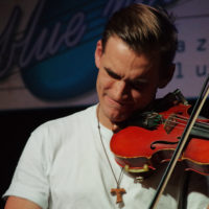 Zdjęcie muzyka grającego na skrzypcach.