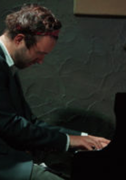 Zdjęcie artysty przy fortepianie.