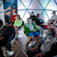 Na zdjęciu grupa ludzi siedząca na fotelach w okularach do oglądania projekcji 3D.