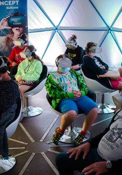 Na zdjęciu grupa ludzi siedząca na fotelach w okularach do oglądania projekcji 3D.