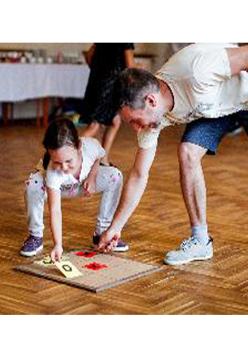 Dziewczynka z ojcem grają w grę planszową leżącą na podłodze.