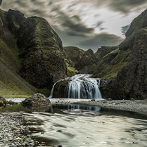Na zdjęciu górzysty krajobraz z niewielkim wodospadem.