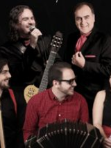 Na zdjęciu pięciu uśmiechniętych muzyków z instrumentami.