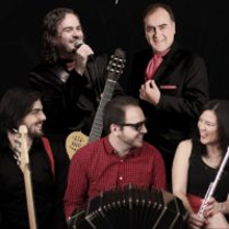 Na zdjęciu pięciu uśmiechniętych muzyków z instrumentami.