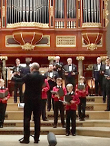 Na zdjęciu chór męski na scenie auli UAM. W tle widoczne piszczałki organów.