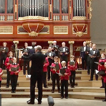 Na zdjęciu chór męski na scenie auli UAM. W tle widoczne piszczałki organów.