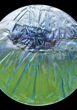 Na zdjęciu na czarnym tle okrąg ze szkła w dolnej części zielonkawy w górnej niebieski.