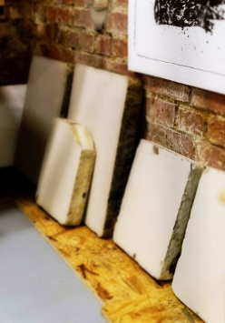 Zdjęcie przedstawia ułożone obok siebie kamienie litograficzne, służące za matryce wykorzystywane w druku litograficznym.