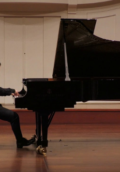 Na zdjęciu mężczyzna siedzący przy fortepianie.