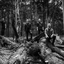 Na czarno-białym zdjęciu trzy postaci mężczyzn w lesie.