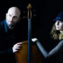 Na zdjęciu dwie postaci opierające się o wiolonczelę.