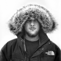 Na zdjęciu młody mężczyzna w zimowej kurtce z założonym na głowę kapturem.